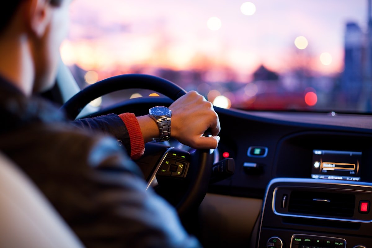 Driver gripping a modern steering wheel inside a vehicle cabin
